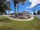 Spacious backyard featuring an outdoor fireplace, screened-in pool area, lush landscaping, and a white privacy fence at 2326 Mountain Ash Way, New Port Richey, FL 34655