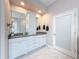 Bathroom with dual sinks, white cabinets, and a large mirror, providing ample space and storage at 2326 Mountain Ash Way, New Port Richey, FL 34655