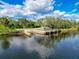Scenic view of a wooden dock extending into the calm waters, surrounded by lush greenery and a serene atmosphere at 2326 Mountain Ash Way, New Port Richey, FL 34655