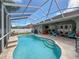 Refreshing screened-in pool area featuring a sparkling pool, paver patio, and comfortable lounge seating for outdoor relaxation at 2326 Mountain Ash Way, New Port Richey, FL 34655