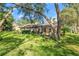 Spacious backyard featuring a screened lanai, lush green lawn, and mature trees at 2342 Countryside Dr, Spring Hill, FL 34606
