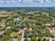 Scenic aerial view of a residential area, showcasing homes surrounded by trees, and an open field under a blue sky at 2404 Knoll Dr, Spring Hill, FL 34608