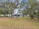 Expansive backyard featuring a screened-in pool and lanai, surrounded by mature trees, creating a serene outdoor oasis at 2404 Knoll Dr, Spring Hill, FL 34608