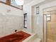 Spacious bathroom featuring a red jacuzzi bathtub, tiled walls, and a glass-enclosed shower at 2404 Knoll Dr, Spring Hill, FL 34608