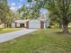 Beautiful front exterior showcasing the home's brick and white siding, spacious driveway and lush, green front yard at 2404 Knoll Dr, Spring Hill, FL 34608