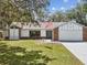 Charming one-story home with brick accents, a well-manicured lawn, and an American flag at 2404 Knoll Dr, Spring Hill, FL 34608