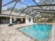 Screened-in pool area with brick pavers, a beautiful blue pool, and an outdoor seating area for relaxation at 2404 Knoll Dr, Spring Hill, FL 34608