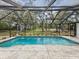 Beautiful in-ground pool with stone surround, screened-in enclosure, and tranquil backyard views at 2404 Knoll Dr, Spring Hill, FL 34608