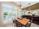Open dining area with wooden table, decorative chandelier, and plantation shutters overlooking the pool at 2987 Wentworth Way, Tarpon Springs, FL 34688
