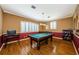 Game room with pool table, chandelier, plantation shutters, decorative wallpaper, and wood floors at 2987 Wentworth Way, Tarpon Springs, FL 34688