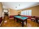 Spacious game room features a pool table, decorative wallpaper, and wood flooring with access to the staircase at 2987 Wentworth Way, Tarpon Springs, FL 34688
