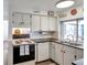 This well-lit kitchen features white cabinets and a large window looking into the patio at 3118 Lloyd Dr, Holiday, FL 34691