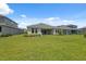 Spacious backyard of the property with healthy green grass and a covered patio at 33466 Landsman Loop, Wesley Chapel, FL 33543