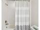 Bathroom with white tiled shower and gray striped shower curtain at 4083 Woods Rider Loop, Odessa, FL 33556