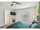 Cozy bedroom features plush teal bedding, modern ceiling fan, mounted TV, and bright natural light at 4083 Woods Rider Loop, Odessa, FL 33556