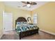 Bedroom featuring a queen bed with leaf-patterned bedding, a ceiling fan, a side table, and yellow walls at 4083 Woods Rider Loop, Odessa, FL 33556