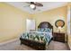 Cozy bedroom with wood ceiling fan, yellow walls, king bed with leaf-patterned bedding and plenty of sunlight at 4083 Woods Rider Loop, Odessa, FL 33556