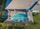 Aerial view of a backyard oasis with a screened-in pool and spa surrounded by lush landscaping, perfect for outdoor enjoyment at 4197 Glade Wood Loop, New Port Richey, FL 34655