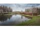 Scenic view of the wooden boardwalk as it extends over the tranquil pond and lush landscape under a cloudy sky at 4197 Glade Wood Loop, New Port Richey, FL 34655