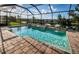 A screened-in pool area featuring a water feature and brick pavers, with views of the serene backyard pond at 4197 Glade Wood Loop, New Port Richey, FL 34655
