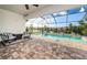Screened-in pool and spa area with brick paver decking, comfortable lounge chairs, and serene waterfront views at 4197 Glade Wood Loop, New Port Richey, FL 34655