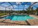 An inviting screened-in pool with a water feature and brick pavers, offering serene views of the backyard pond at 4197 Glade Wood Loop, New Port Richey, FL 34655