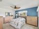 Bright bedroom with a blue accent wall, ceiling fan, window, and bed with a coastal-themed comforter at 4567 Great Lakes S Dr, Clearwater, FL 33762