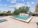 A bright, tiled pool with surrounding lounge chairs and shaded areas under a sunny, partly cloudy sky at 4567 Great Lakes S Dr, Clearwater, FL 33762