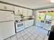 Bright kitchen with white appliances, tile floors, and a sliding glass door leading to the outside patio at 4628 Irene Loop, New Port Richey, FL 34652
