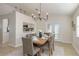 Bright dining room featuring a wooden table, gray chairs, a modern chandelier, and an open view to the kitchen at 4752 Weasel Dr, New Port Richey, FL 34653