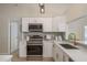 Modern kitchen featuring white cabinets, stainless appliances, white countertops, and a stylish backsplash at 4752 Weasel Dr, New Port Richey, FL 34653