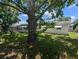View of the home's backyard, showing a large tree, a screened-in porch, and awning-covered windows at 4853 Alcea St, New Port Richey, FL 34652