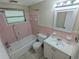 Cozy bathroom with pink tile, tub, vanity and natural light from the window at 4853 Alcea St, New Port Richey, FL 34652
