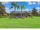 Well-maintained backyard featuring a screened-in pool area, palm trees, and manicured lawn at 5121 Delacroix Dr, Brooksville, FL 34604