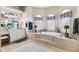 Bathroom with a tub, tile flooring, and an abundance of natural light from the three windows at 5121 Delacroix Dr, Brooksville, FL 34604