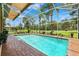 Screened-in pool with clear blue water, surrounded by brick pavers and lush landscaping at 5121 Delacroix Dr, Brooksville, FL 34604