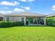 A covered patio with outdoor furniture extends from the rear of this home, overlooking a well-manicured lawn at 6130 Colmar Pl, Apollo Beach, FL 33572
