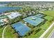 Aerial view of community basketball and tennis courts, with lush landscaping and a beautiful lake backdrop at 6130 Colmar Pl, Apollo Beach, FL 33572