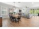 Open-concept dining room with wood table, black chairs, and view of the living room with gray sofa and tile floors at 6130 Colmar Pl, Apollo Beach, FL 33572
