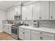 Gourmet kitchen featuring white cabinets, stainless appliances, quartz countertops, and mosaic tile backsplash at 6130 Colmar Pl, Apollo Beach, FL 33572