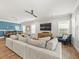 Spacious living room featuring a large gray sofa, hardwood floors, and a mounted television at 6130 Colmar Pl, Apollo Beach, FL 33572
