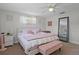 Light-filled bedroom featuring a bed with a pink blanket, pink pillows and a vanity at 6144 Glenwood Dr, New Port Richey, FL 34653