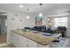 Open kitchen with white cabinets, granite countertops, and a view into the cozy living room at 6144 Glenwood Dr, New Port Richey, FL 34653