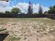Large backyard with wood fence around the property, some grass growing in spots, with blue skies at 6932 Pin Cherry Ln, Port Richey, FL 34668