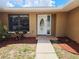 Close-up of the front entrance with a decorative white door, sidelight, and manicured landscaping at 6932 Pin Cherry Ln, Port Richey, FL 34668