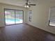 Open living room boasts sliding glass doors to the screened-in pool area and wood-look floors at 6932 Pin Cherry Ln, Port Richey, FL 34668