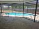 View of pool and large deck area, with black metal safety railing and screen and a view of the fenced backyard at 6932 Pin Cherry Ln, Port Richey, FL 34668