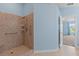 Walk-in shower with tile surround and convenient grab bars in a well lit primary bathroom at 7059 Wirevine Dr, Brooksville, FL 34602
