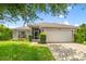 Inviting single-story home with a two-car garage, neutral color palette, and a well-kept lawn at 7059 Wirevine Dr, Brooksville, FL 34602