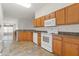 Bright kitchen featuring wooden cabinets, white appliances, and tile flooring at 7059 Wirevine Dr, Brooksville, FL 34602